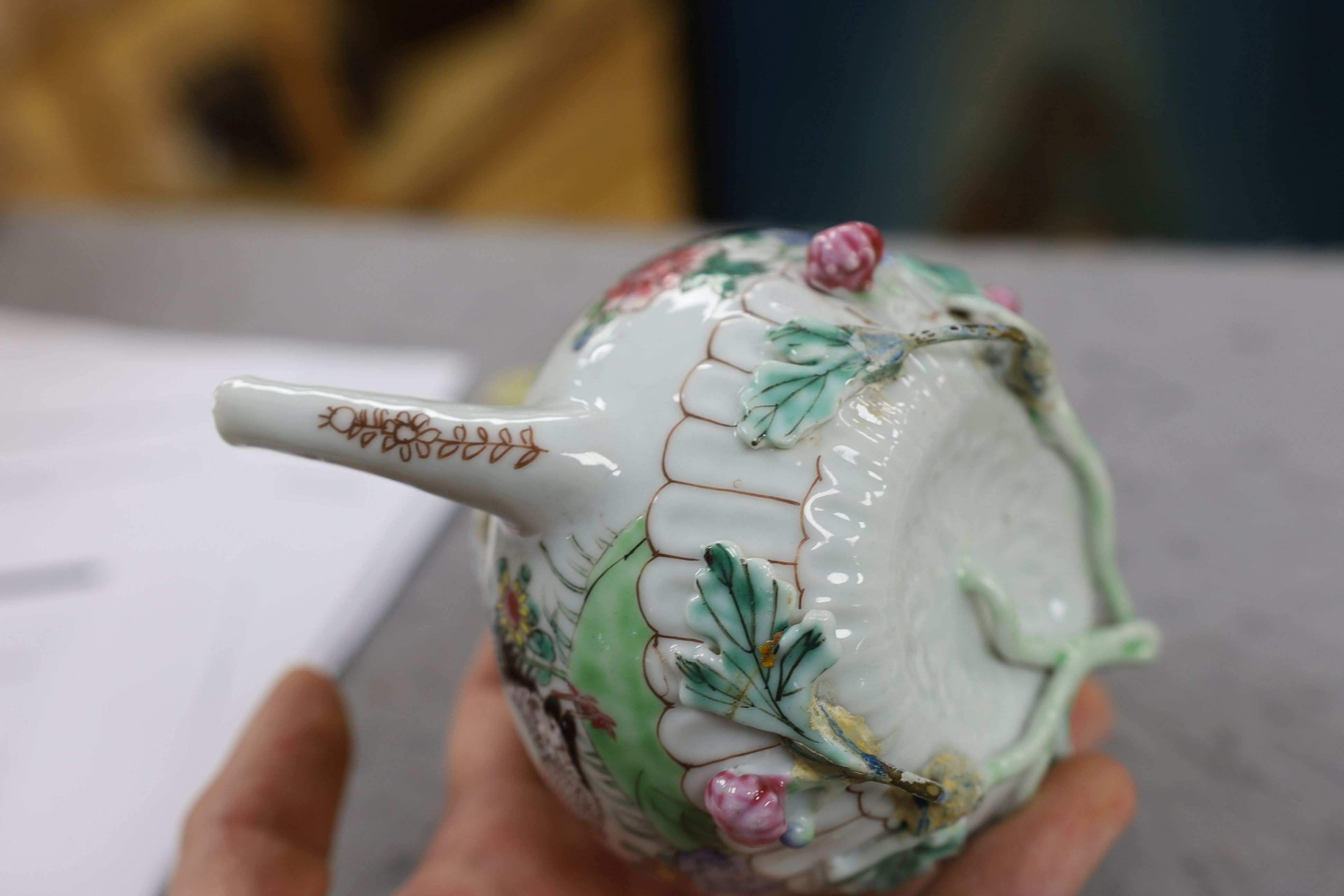 A Chinese famille rose chrysanthemum moulded teapot, early Qianlong period, painted with a cockerel amongst flowers, on a cage work base, 10 cms high
